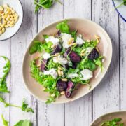 Overhead shot of beetroot salad on a white wooden background with rocket leaves