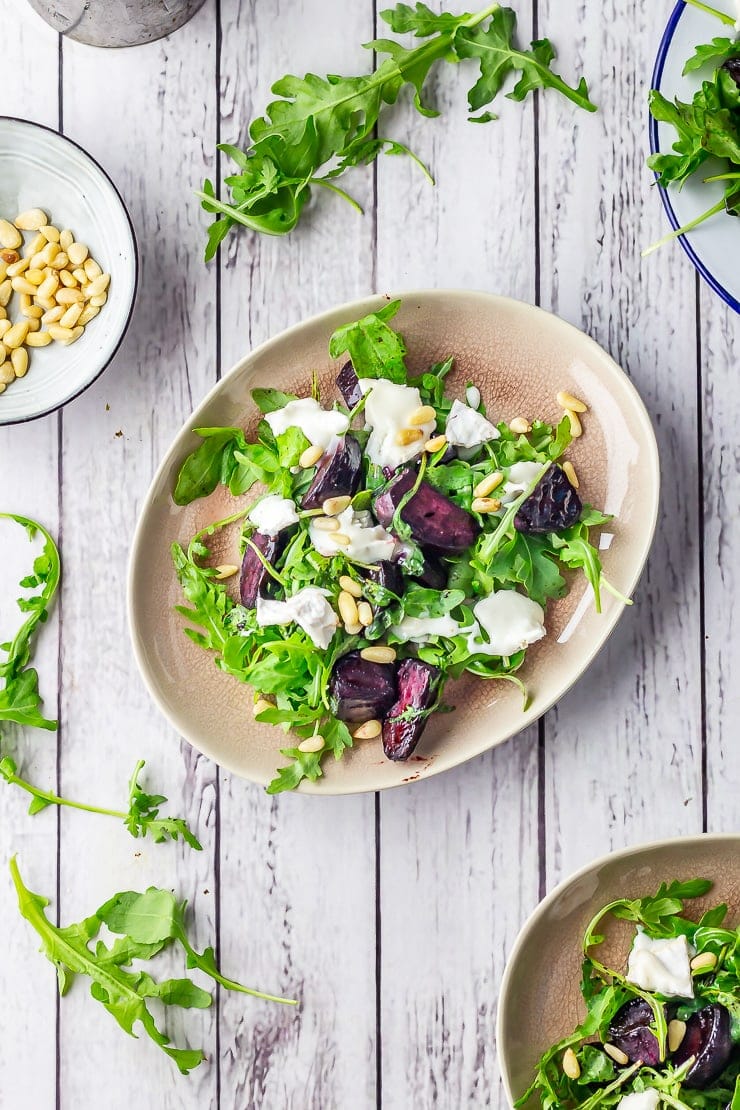 Overhead shot of beetroot salad on a white wooden background with rocket leaves