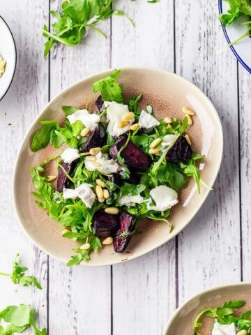 Overhead shot of beetroot salad with goat's cheese on a white wooden background