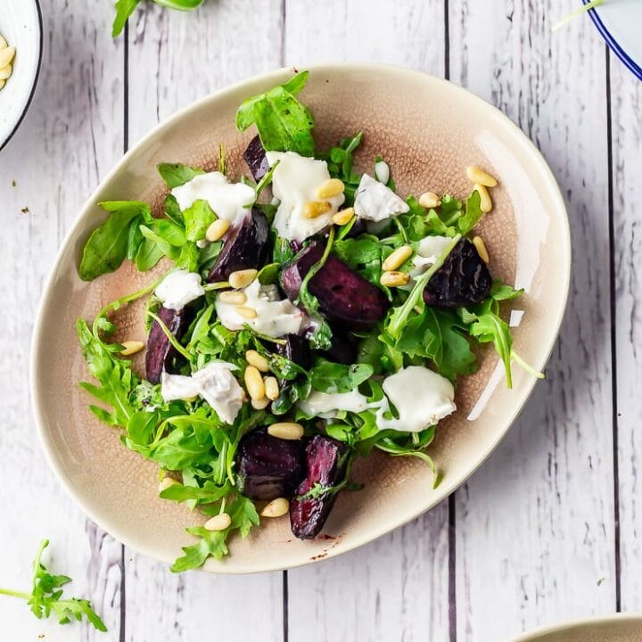 Overhead shot of beetroot salad with goat's cheese on a white wooden background