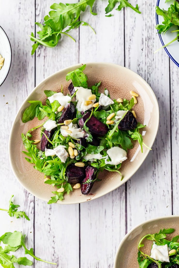 Overhead shot of beetroot salad with goat's cheese on a white wooden background