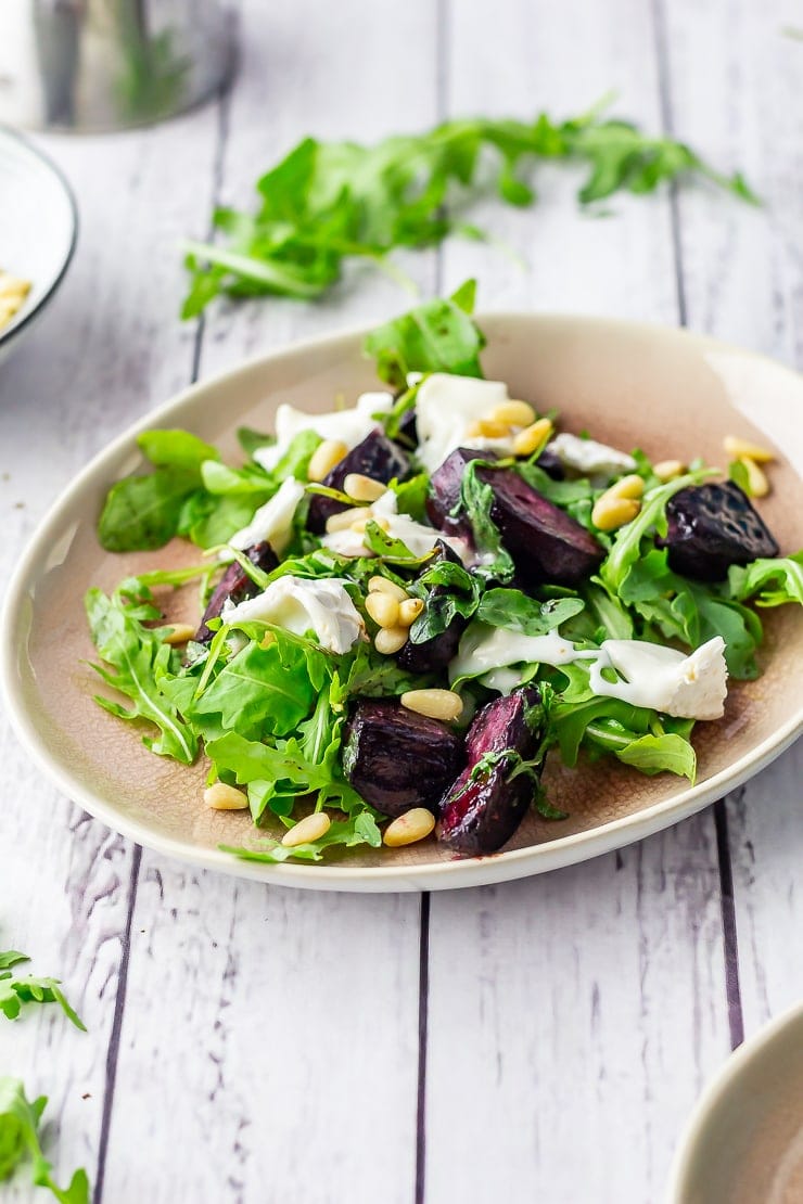 Side on shot of beetroot salad on a pink plate over a white wooden background