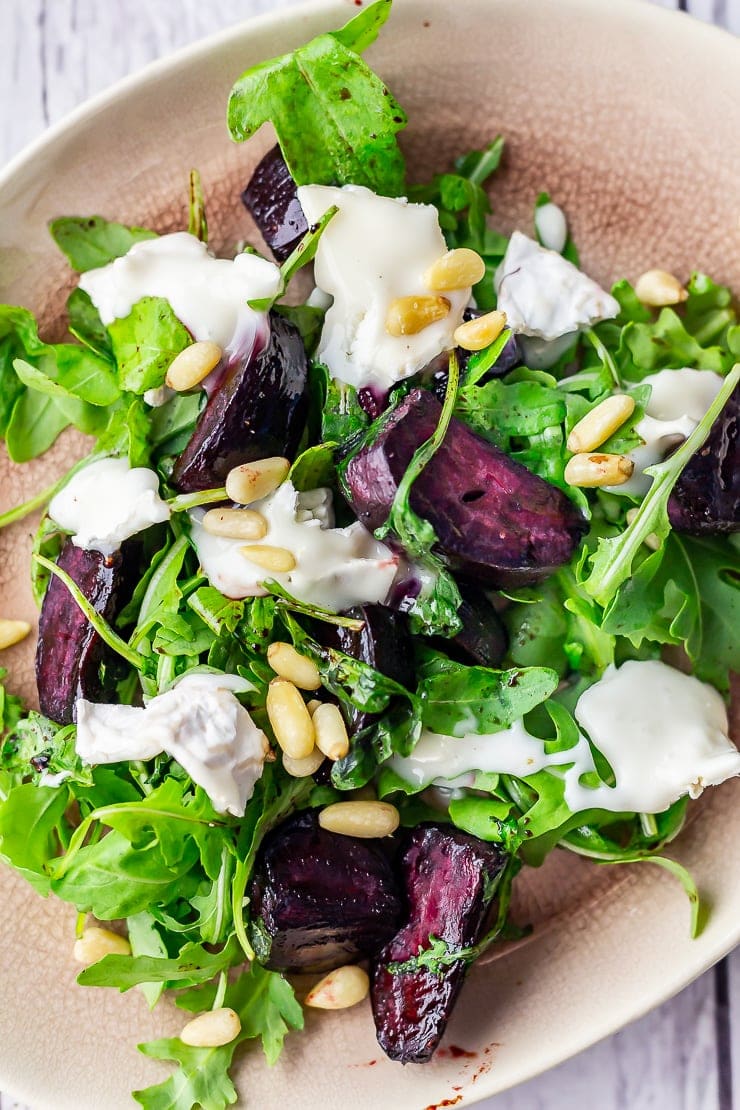 Overhead close up of beetroot salad with goat's cheese on a pink plate