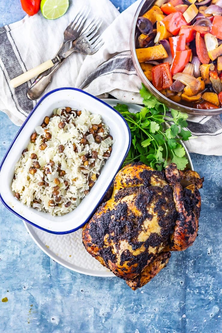 Overhead shot of jerk roasted chicken with rice and coconut curry on a blue background