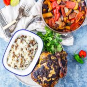 Overhead shot of jerk roasted chicken with rice and coconut curry on a blue background