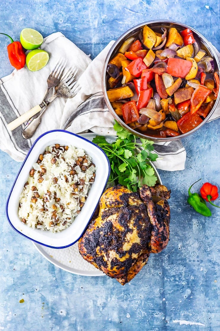 Overhead shot of jerk roasted chicken with coconut curry and rice on a blue background