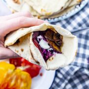 Hand holding a mushroom wrap over a checked cloth background