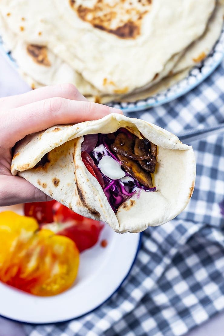 Hand holding a mushroom wrap over a checked cloth background