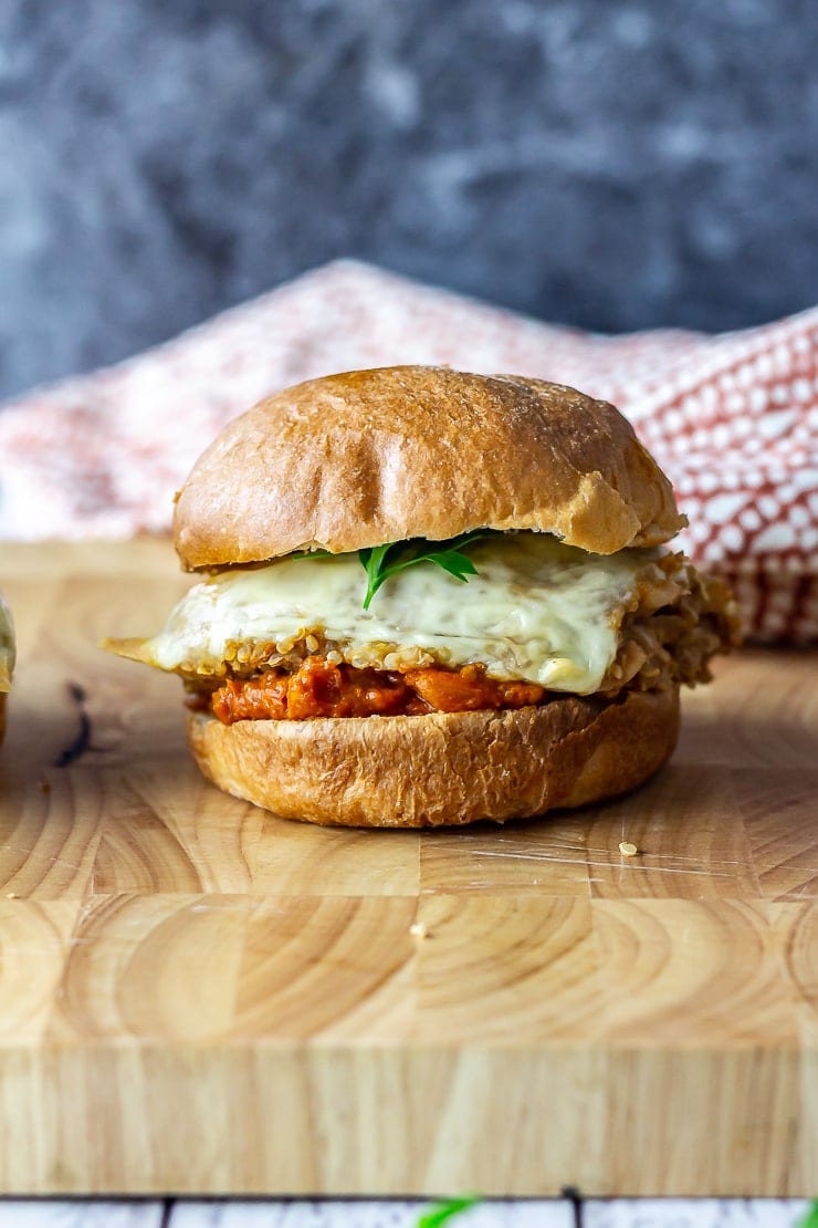 Side on shot of veggie burger on a wooden board with a cloth in the background