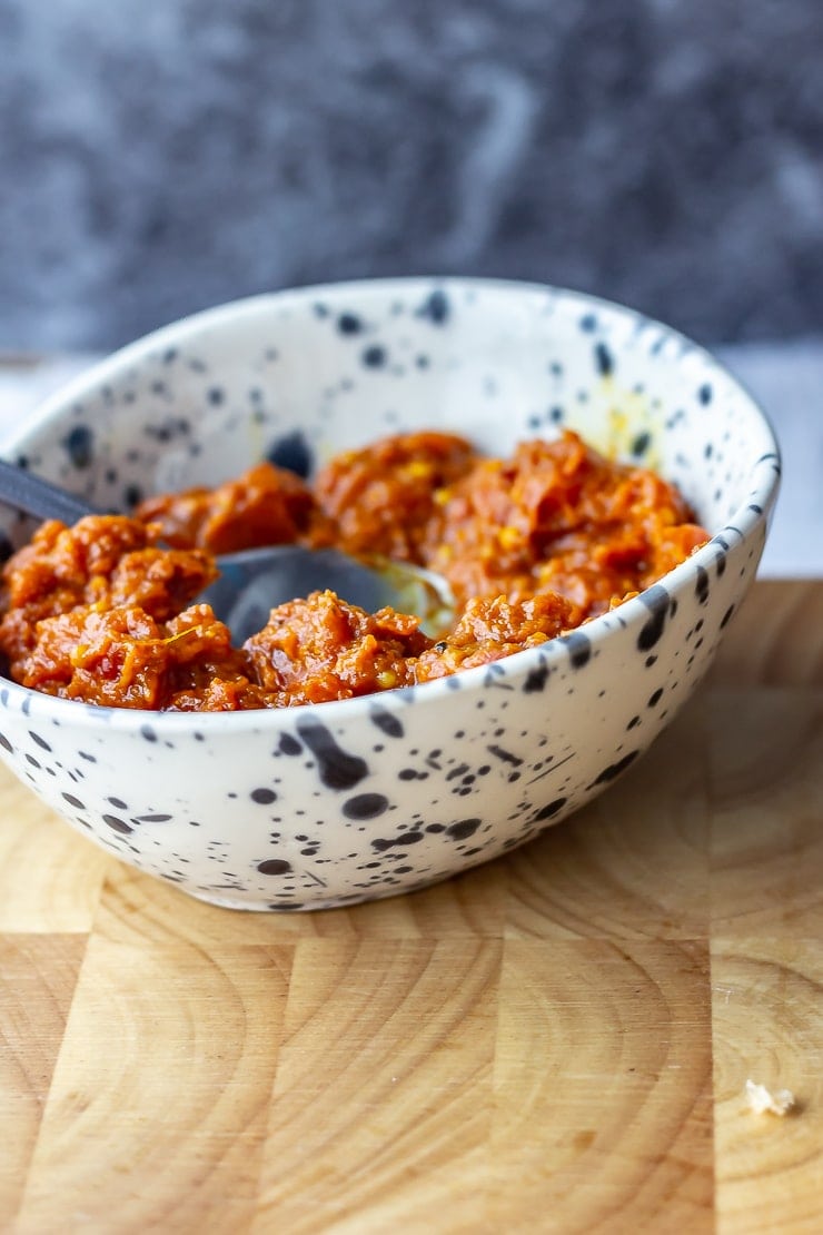 Bowl of harissa to go with veggie burgers on a wooden board