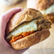 Hand holding a veggie burger with quinoa