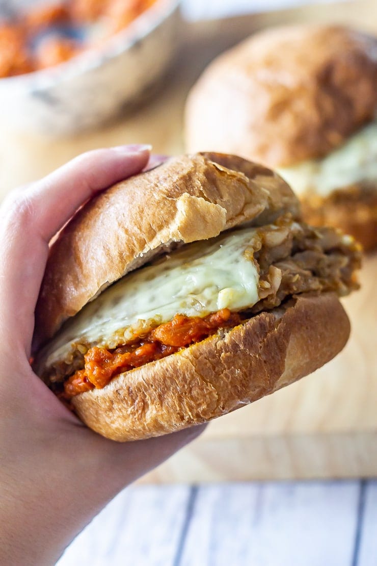 Hand holding a veggie burger with quinoa