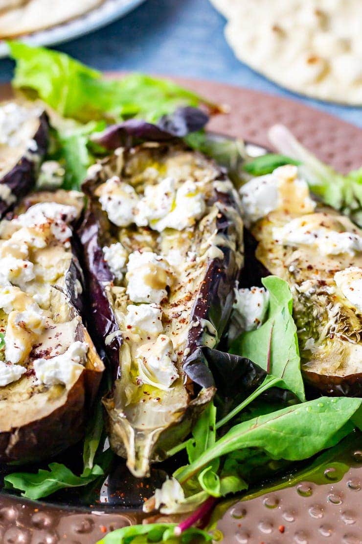 Close up of baked aubergine with goat's cheese on a platter with salad leaves