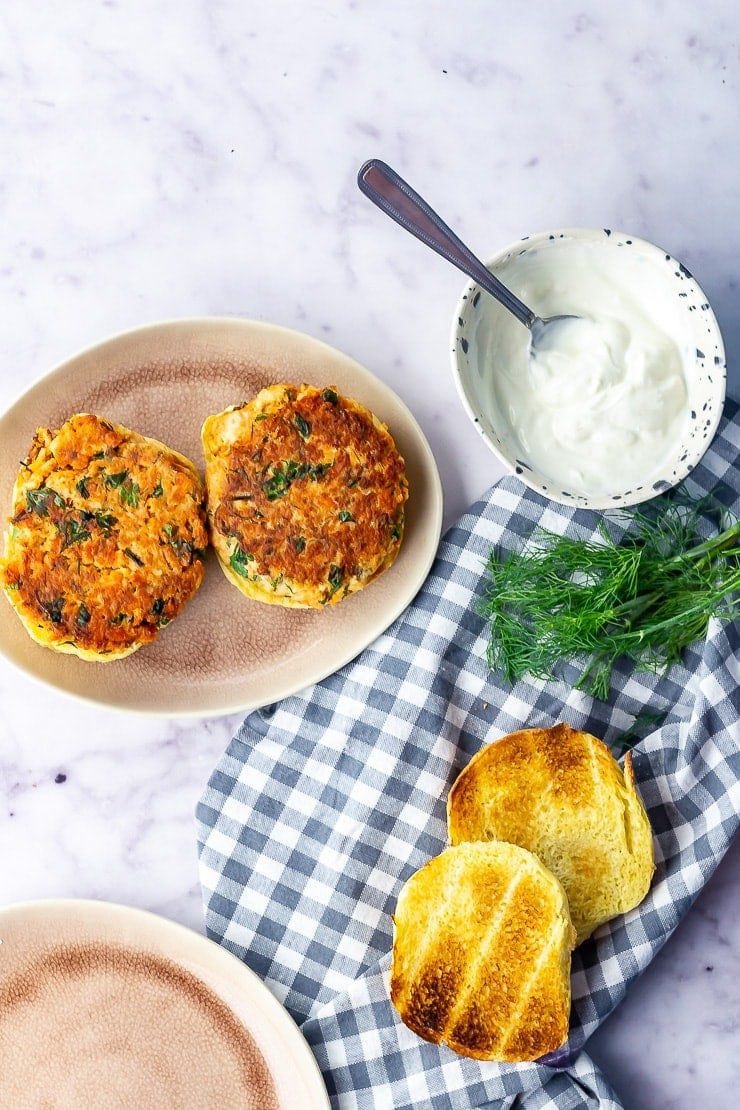 Overhead shot of salmon burgers with toasted brioche on a checked cloth over a marble background