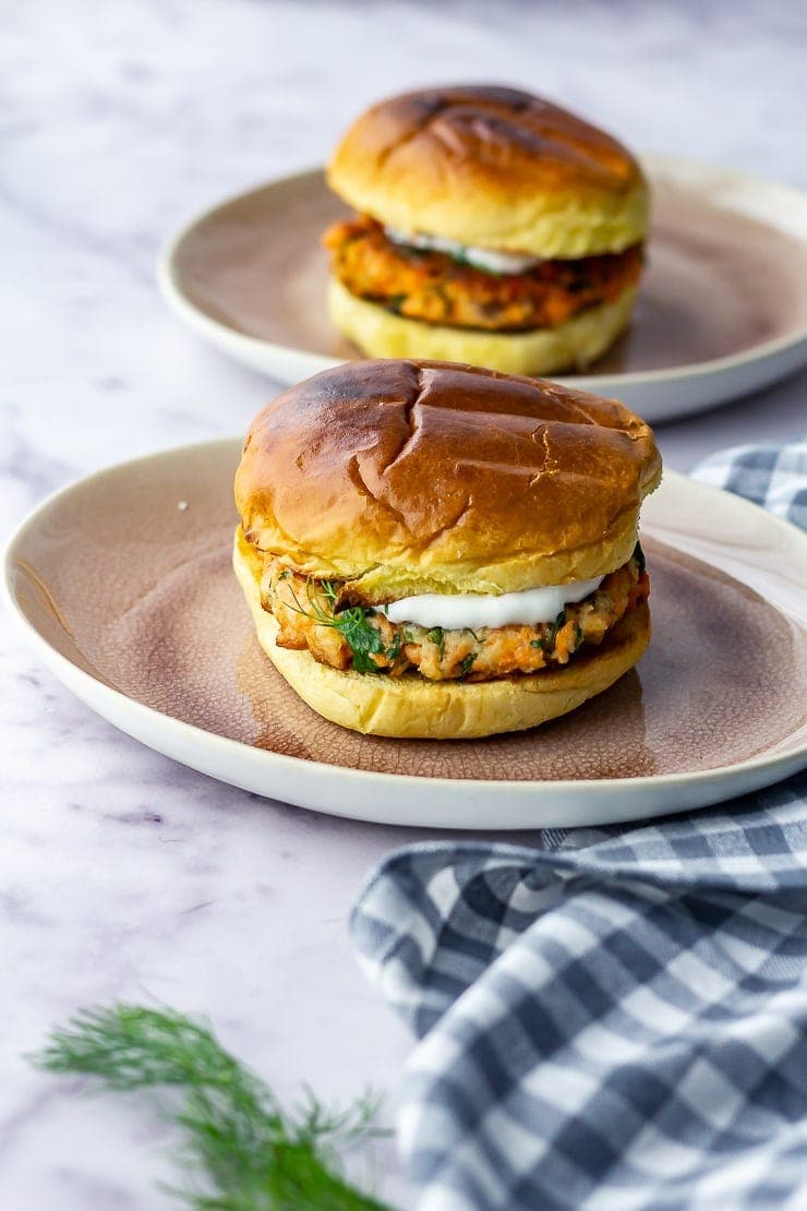 Two salmon burgers on a checked cloth over a marble background
