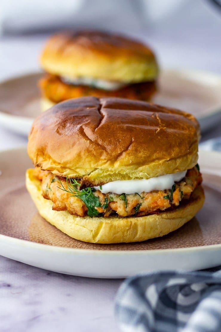 Side on shot of salmon burger on a plate over a marble background