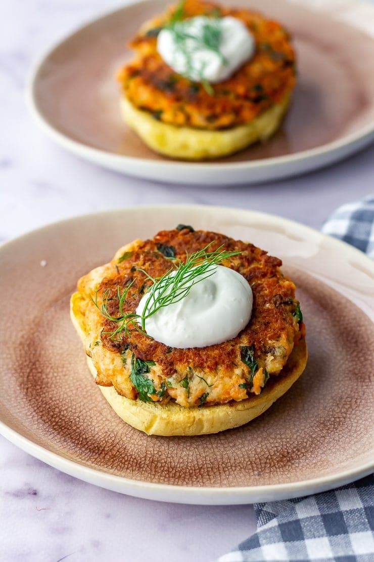 Two salmon burgers on pink plates on a marble background