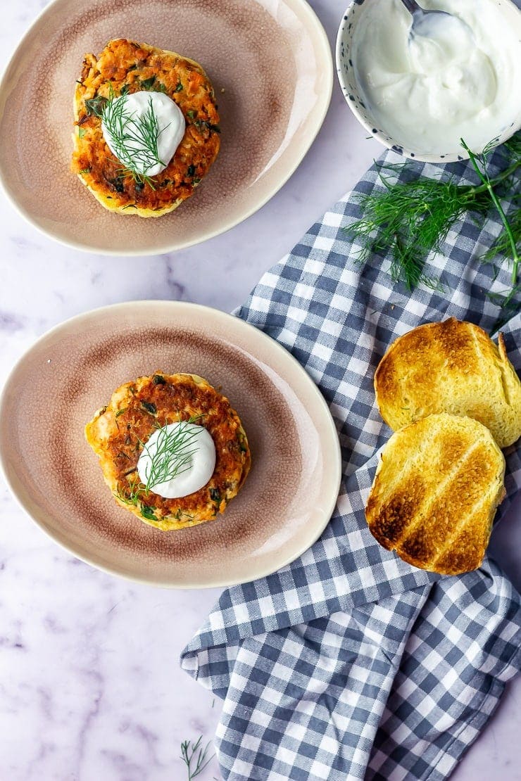 Overhead shot of salmon burgers with a check cloth and burger buns over a marble background