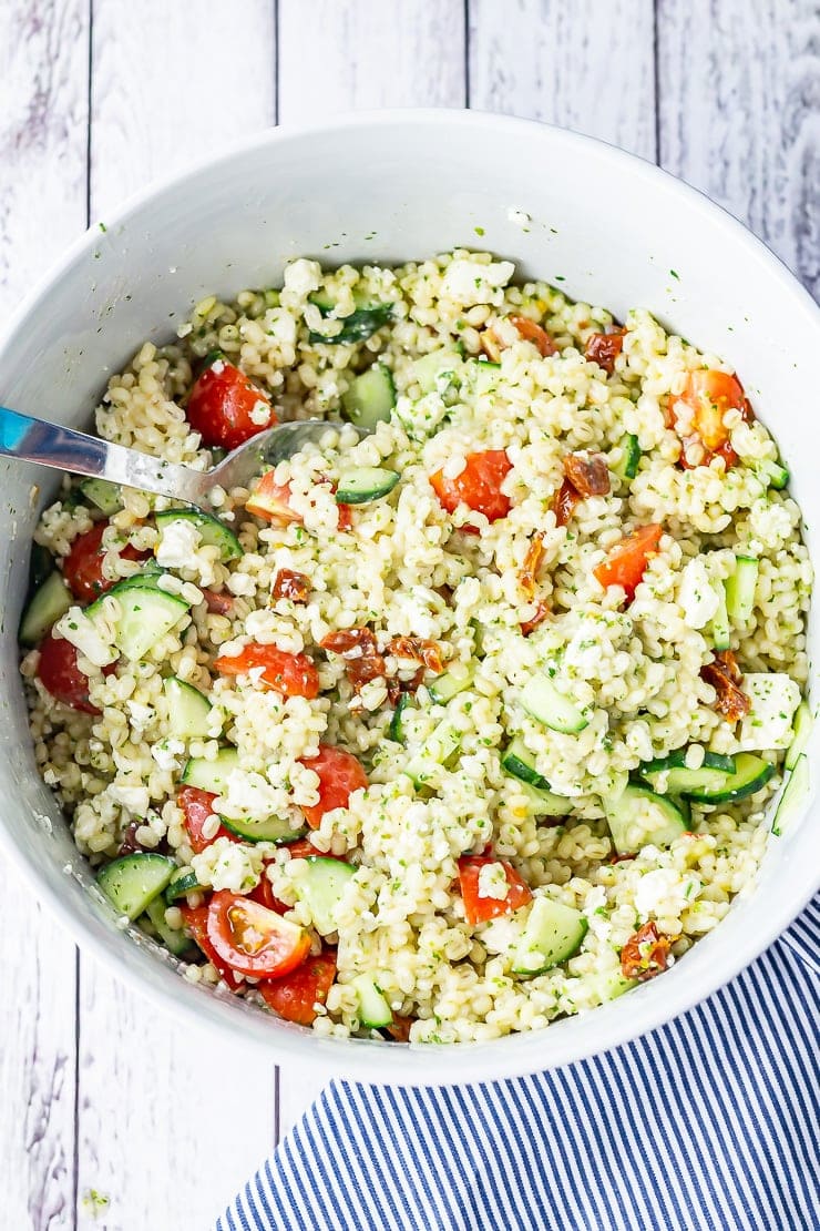 Overhead shot of summer salad with pearl barley on a white wooden background