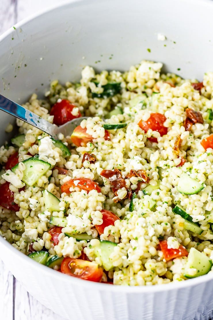 Summer salad with pearl barley in a bowl with a spoon