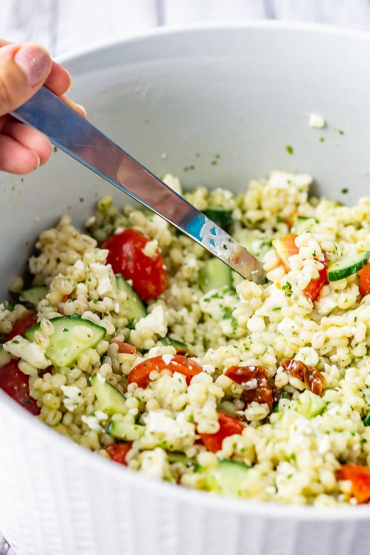 Bowl of summer salad with pearl barley with a spoon