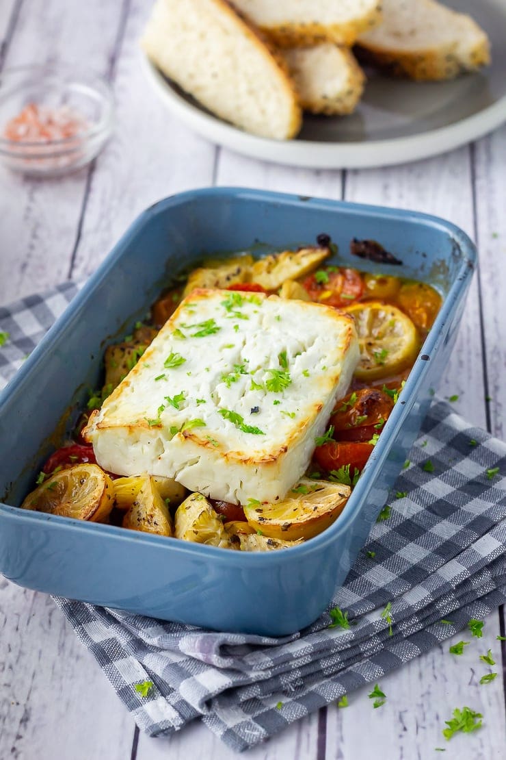 Baked feta with vegetables in a blue baking dish on a checked cloth