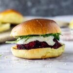 Side on shot of beetroot burger with whipped feta on a marble background