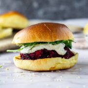 Side on shot of beetroot burger with whipped feta on a marble background