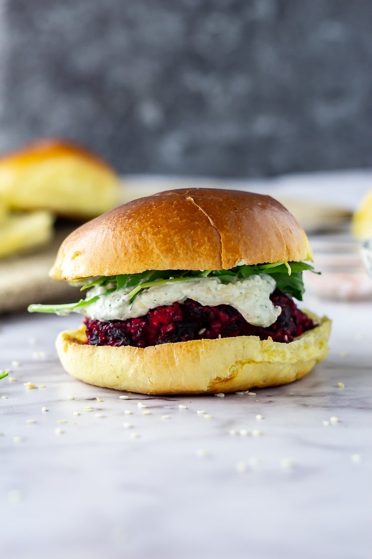 Side on shot of beetroot burgers with whipped feta on a marble background