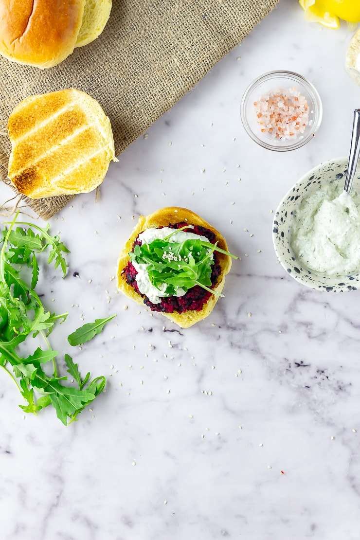 Overhead shot of beetroot burgers with whipped feta on a marble background