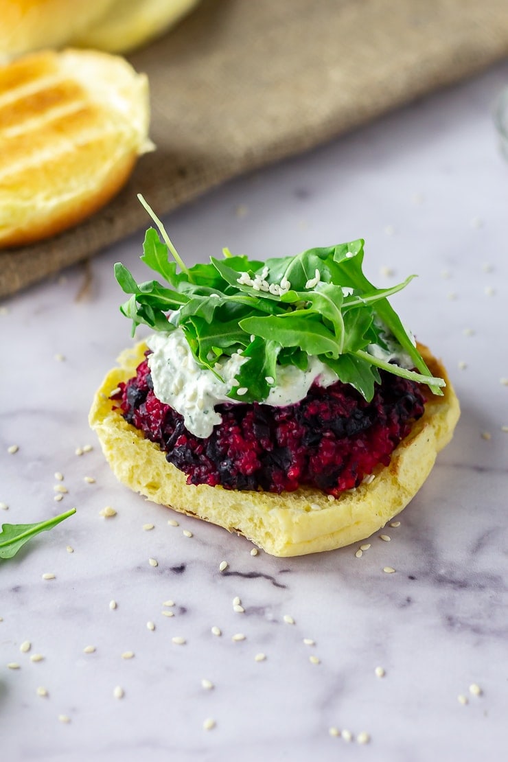 Beetroot burgers topped with whipped feta and rocket on a marble background