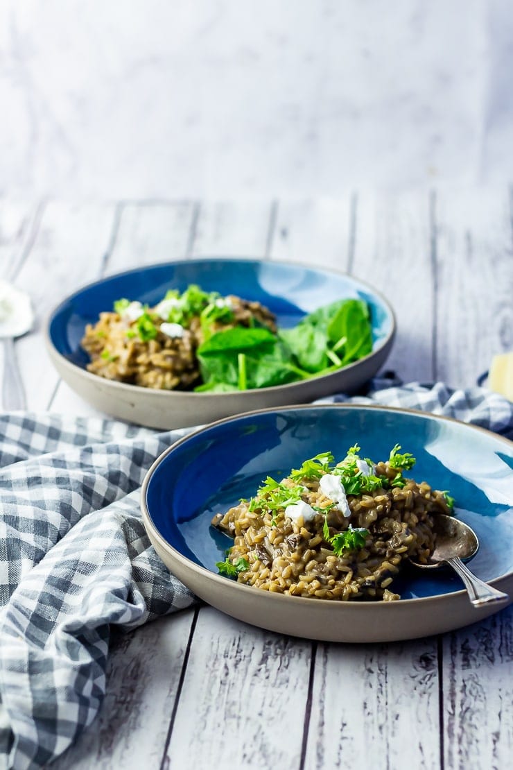 Side on shot of black garlic risotto on a white wooden background with a checked cloth