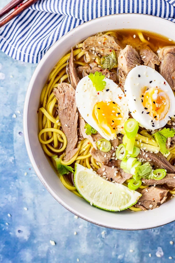 Overhead shot of leftover turkey soup topped with an egg on a blue background