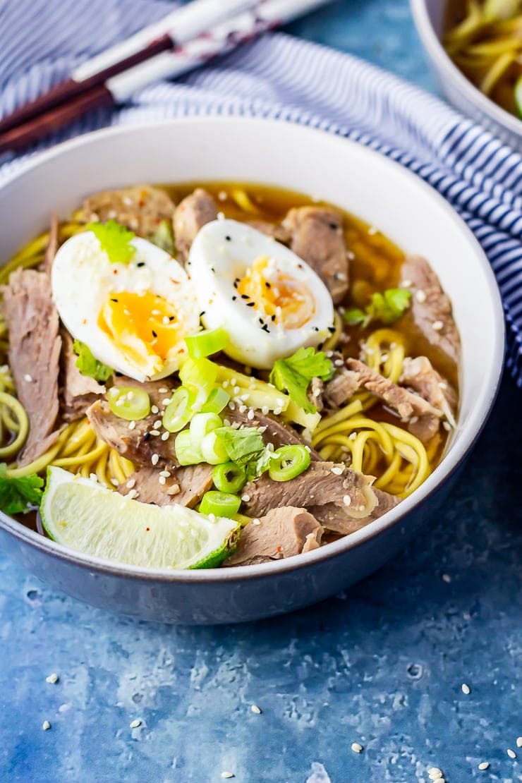 Angled shot of leftover turkey soup with a boiled egg on a blue background