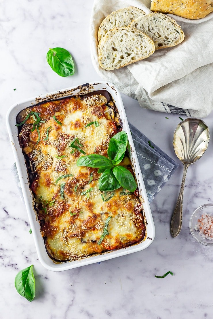 Overhead shot of aubergine parmigiana on a marble background with bread