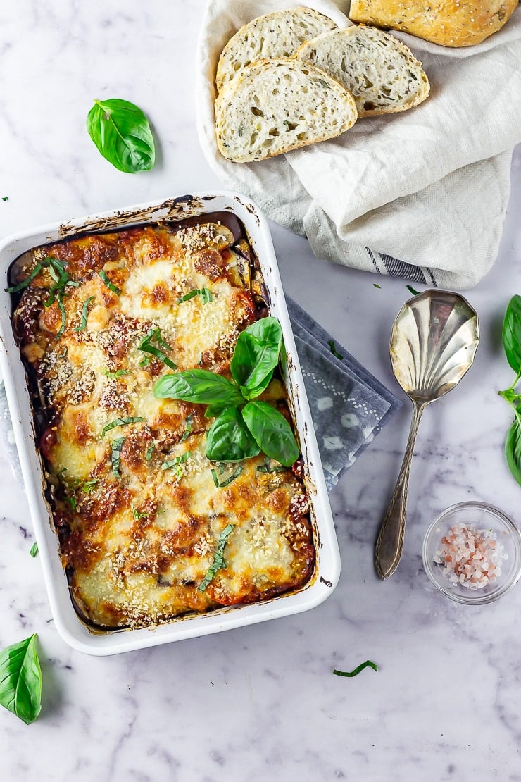 Overhead shot of aubergine parmigiana on a marble background with bread