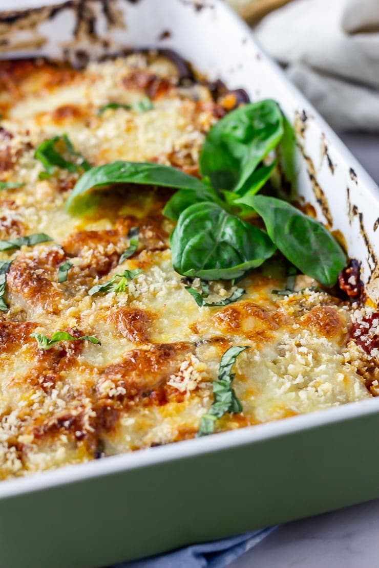 Close up of aubergine parmigiana in a green baking dish