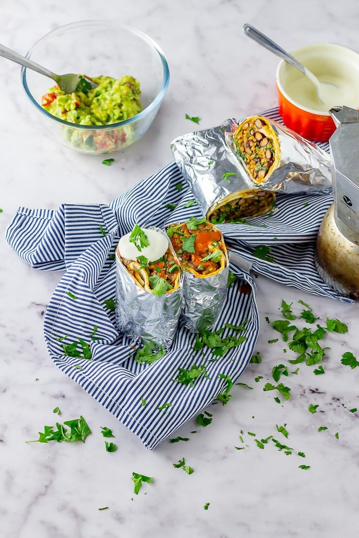 Vegetarian breakfast burrito on a striped cloth over a marble background