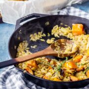 One pot orzo with roasted butternut squash in a cast iron skillet on a checked cloth
