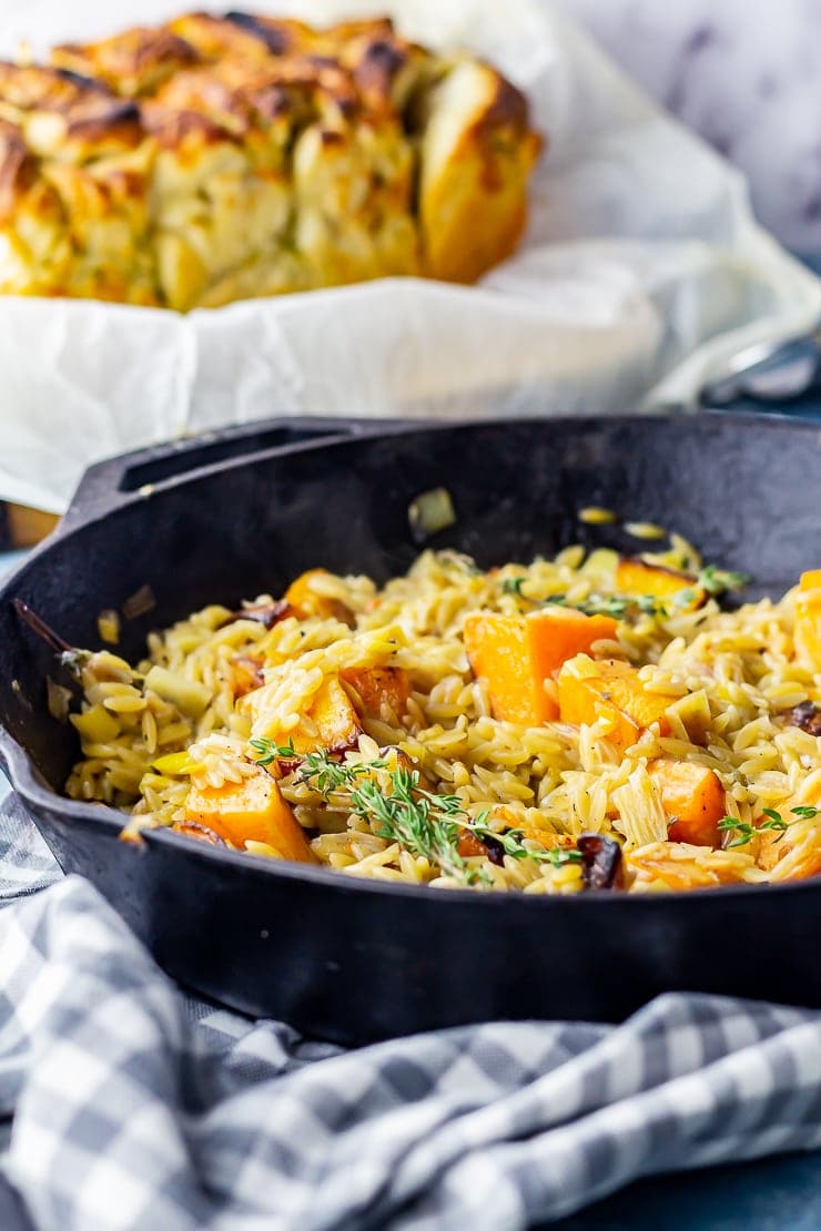 Side on shot of one pot orzo with butternut squash in a skillet on a checked cloth