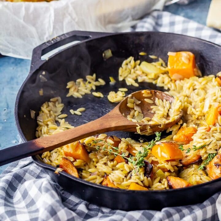 One pot orzo with butternut squash with a wooden spoon and checked cloth