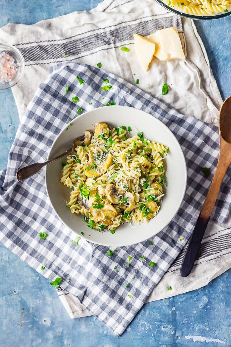 Overhead shot of mushroom pasta on a checked cloth with parmesan