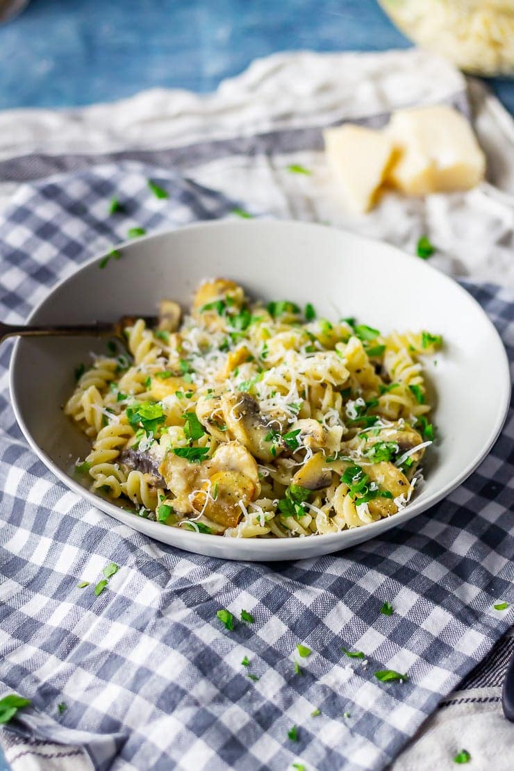 Side on shot of mushroom pasta with a fork on a checked background
