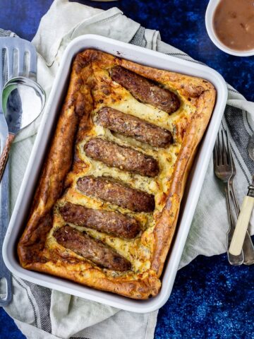 Overhead shot of vegetarian toad in the hole on a cloth over a blue background
