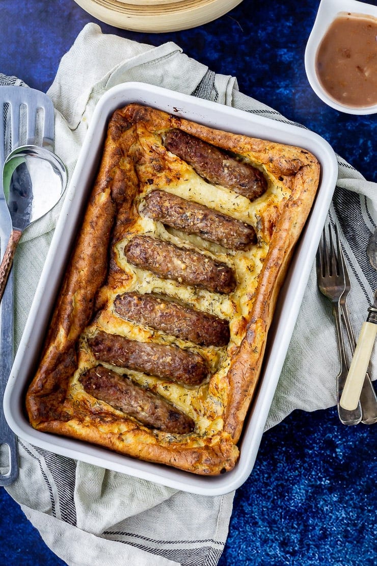 Overhead shot of vegetarian toad in the hole on a cloth over a blue background