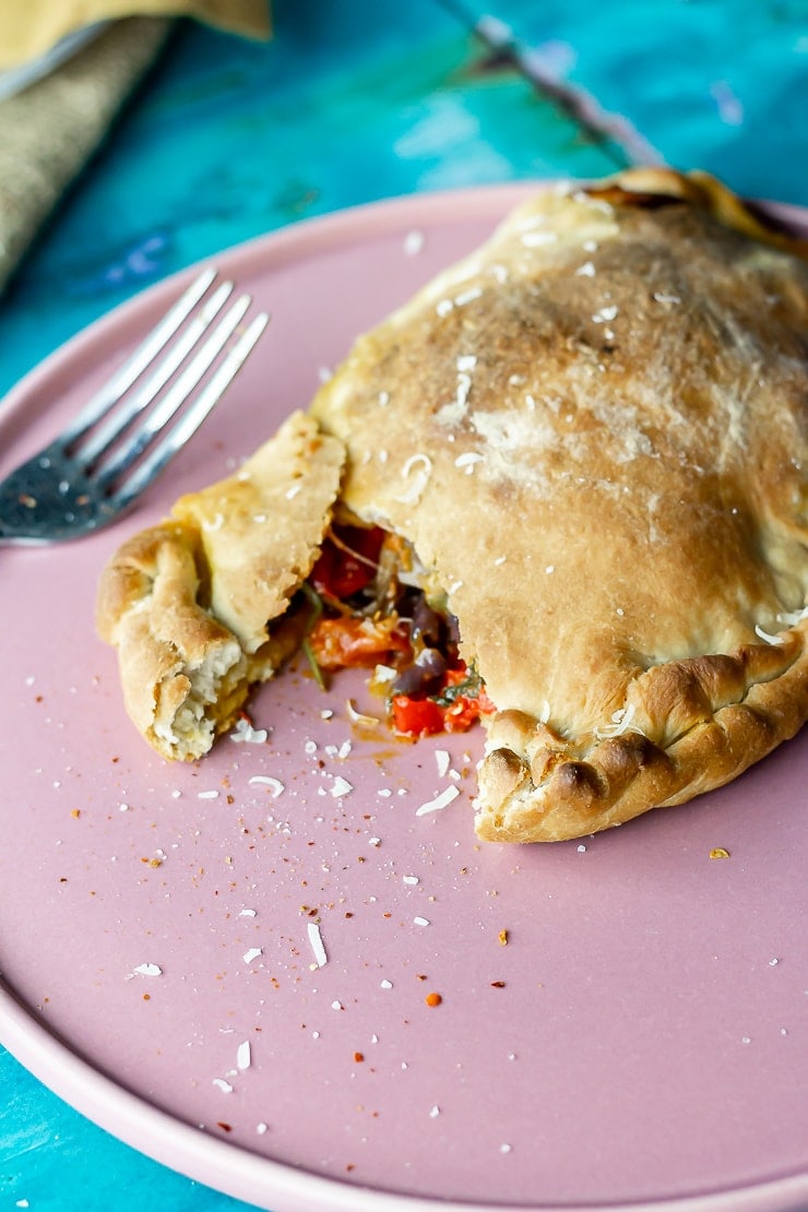 Vegetable calzone on a pink plate with a fork