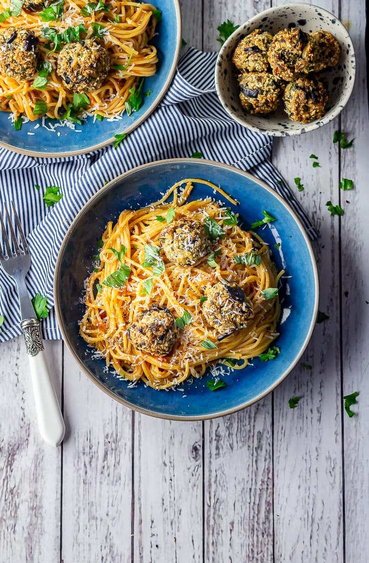 Overhead shot of vegetarian spaghetti and meatballs in a blue bowl on a white wooden background