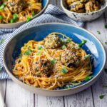 Vegetarian spaghetti and meatballs in a blue bowl on a white wooden background