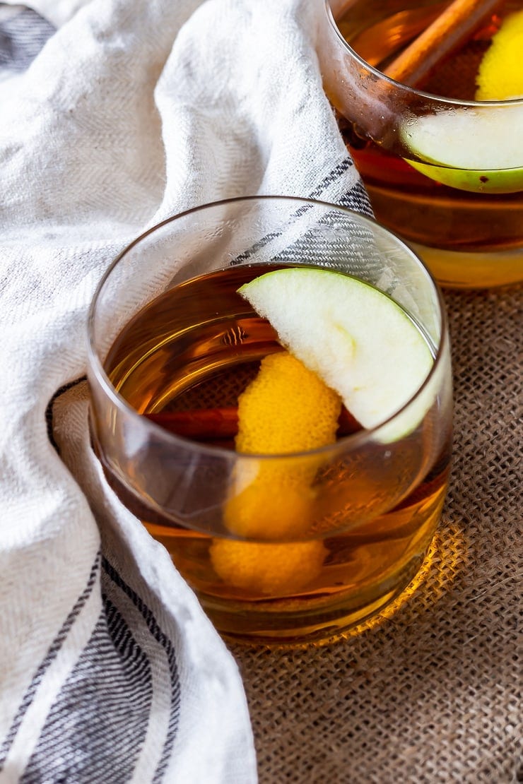Glass of spiced apple cocktail with rum on a mat with a cloth