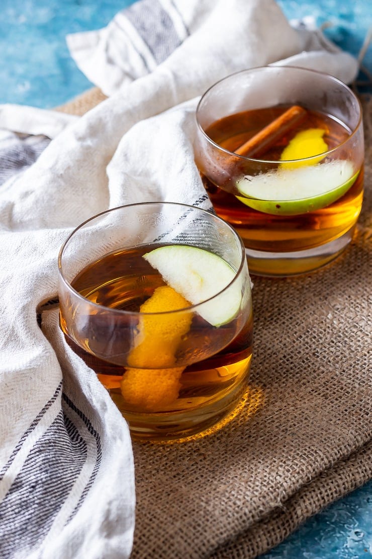 Two glasses of spiced apple cocktail with rum on a mat with a cloth